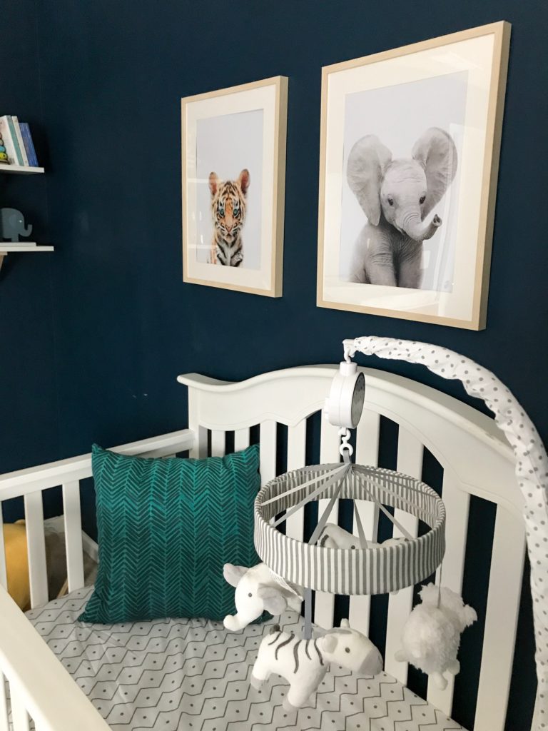 dark blue nursery, navy blue nursery, moody nursery, animal print, safari theme nursery, tribal nursery, lion rocker, tarva dresser, Ikea dresser hack, white crib, tiger print, elephant print, lion print, tribal rug, nursery books  