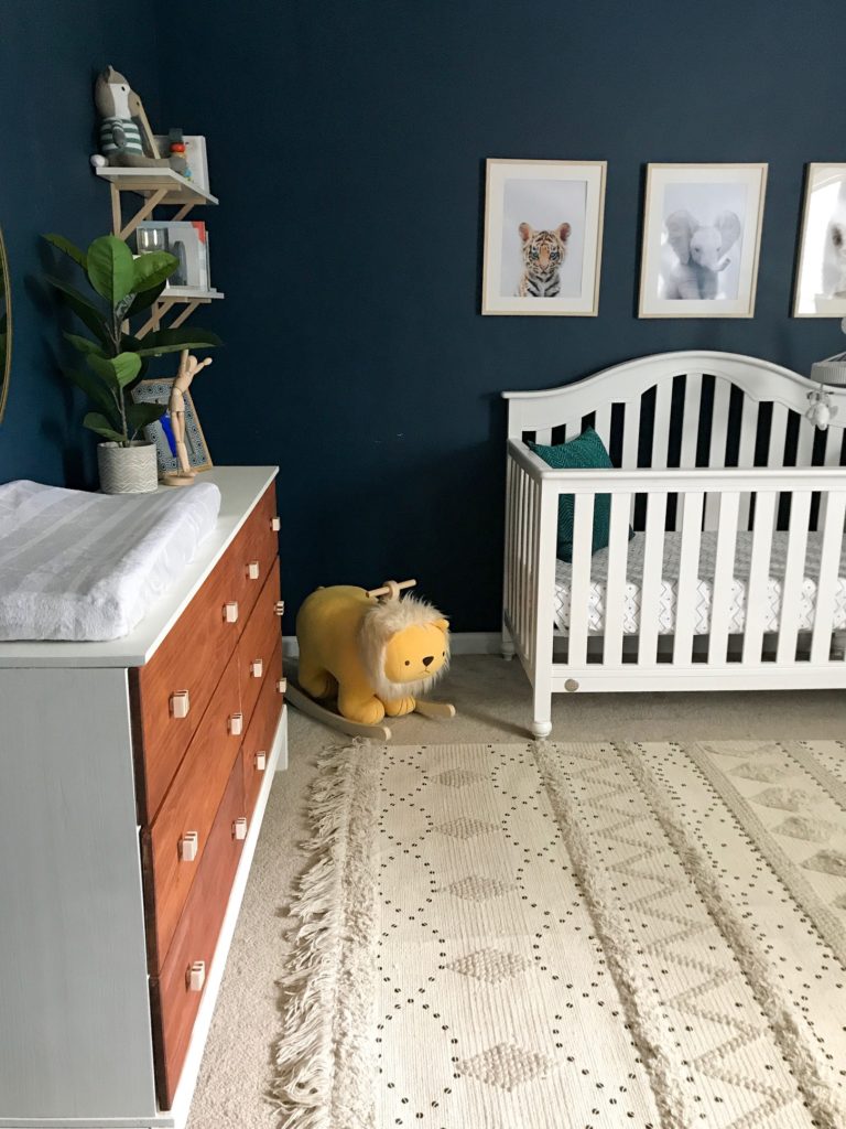 dark blue nursery, navy blue nursery, moody nursery, animal print, safari theme nursery, tribal nursery, lion rocker, tarva dresser, Ikea dresser hack, white crib, tiger print, elephant print, lion print, tribal rug, nursery books  
